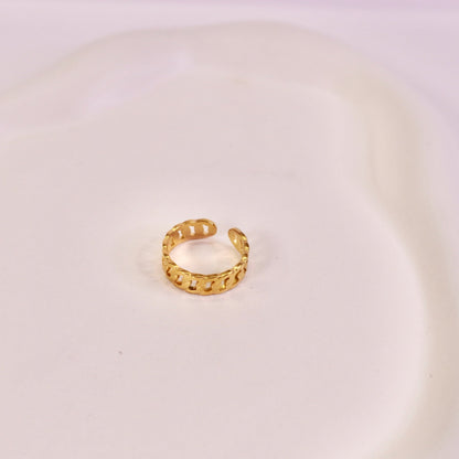 Gold hoop earring on a white plate with a light purple background