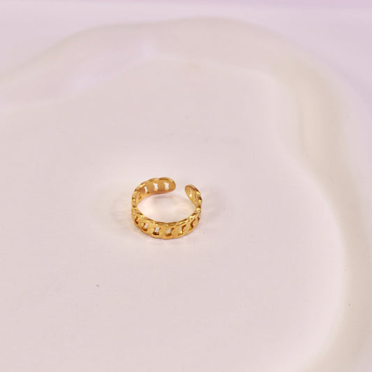 Gold hoop earring on a white plate with a light purple background